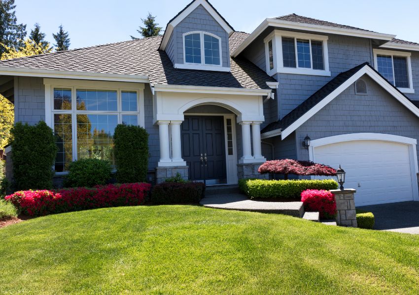 exterior of a two-storey blue home with a white garage door and lush green lawn